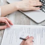 One person on laptop, another person completing a mortgage form
