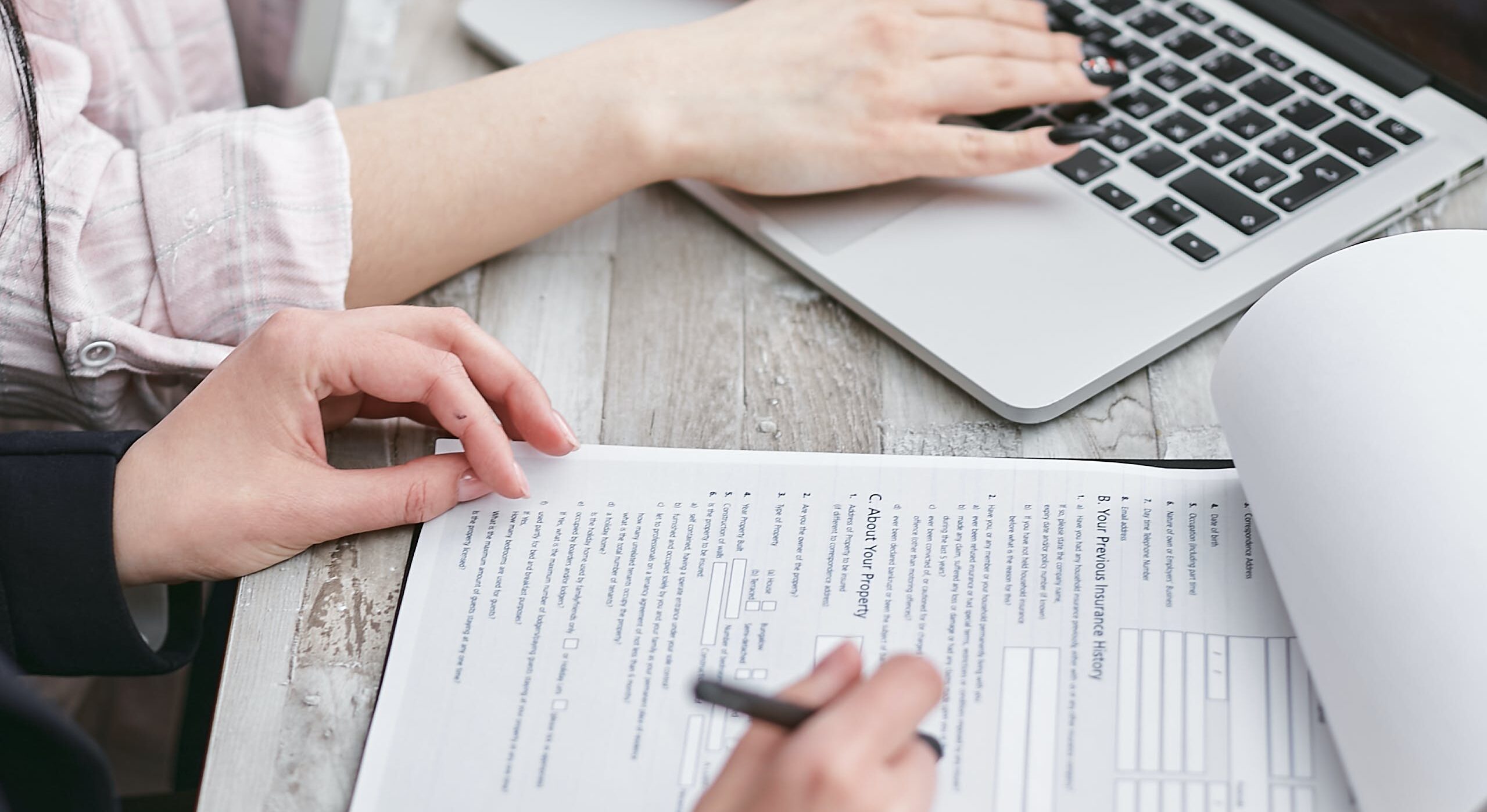 One person on laptop, another person completing a mortgage form